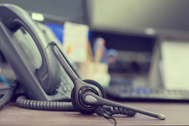 istock close up focus on call center headset device at telephone VOIP system at office desk for hotline telemarketing concept 983443140