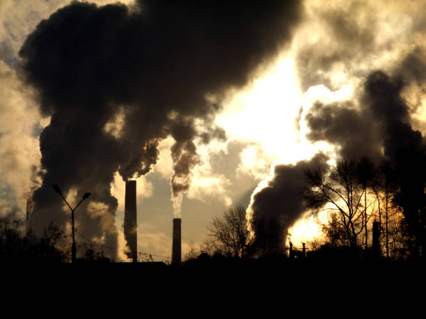 istock Smoking factory chimneys in morning backlighted by rising sun 983443164