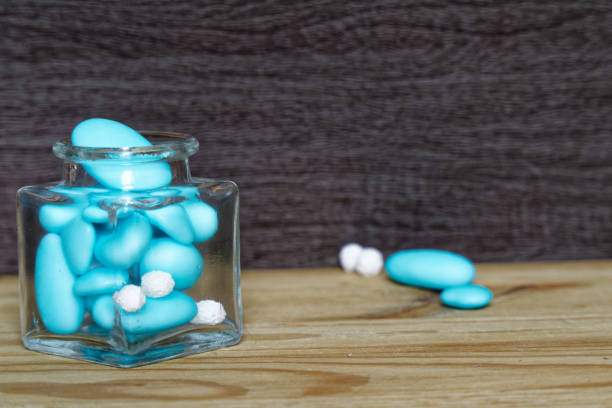 istock Decorative jar with bow and blue stones inside on wooden table, mockup for postcard or greeting card 983457844
