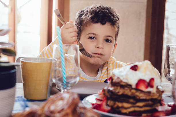 istock Cute little boy sitting around kitchen table waiting for breakfast 983457896