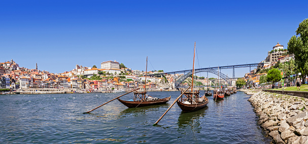 The iconic Rabelo Boats, the traditional Port Wine transports, with the Ribeira District and the Dom Luis I Bridge over the Douro River. Porto, Portugal. Unesco World Heritage.