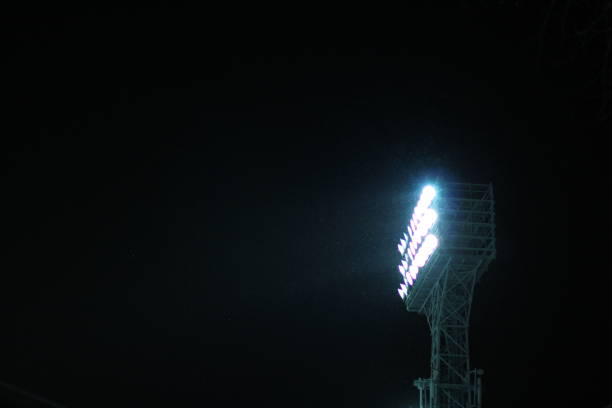istock Stadium Spot-light tower during snowfall against dark night sky background 983479296