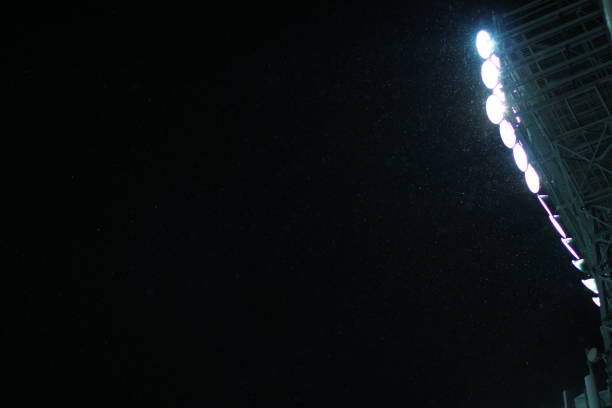 istock Stadium Spot-light tower during snowfall against dark night sky background 983479348