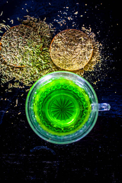 Closes up of essential tea of raw fresh fennel seeds with raw fennel seeds in a transparent cup on wooden surface for good skin and inhibits muscles spasms and helps for a good digestion. stock photo