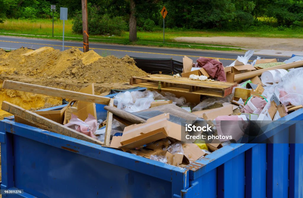 Blue construction debris container filled with rock and concrete rubble. Industrial garbage bin Industrial garbage bin blue construction debris container filled with rock and concrete rubble. Garbage Stock Photo