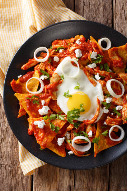 istock Mexican breakfast: chilaquiles with egg and chicken close-up. Vertical top view 983517092