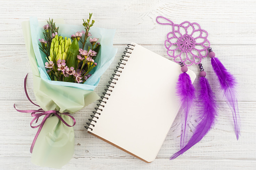 Open empty notebook with bouquet and purple dream catcher