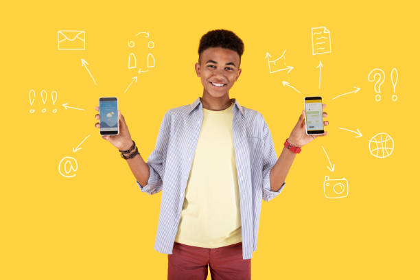 istock Positive young boy holding two smartphones and smiling happily 983536718