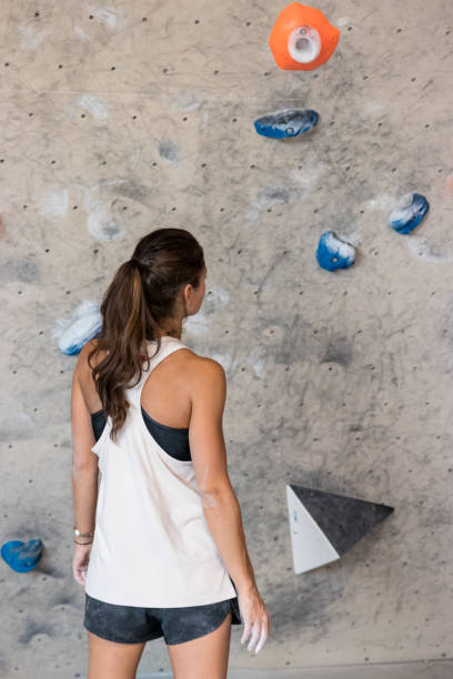 young woman looking at a climbing wall - women moving up looking human hair imagens e fotografias de stock