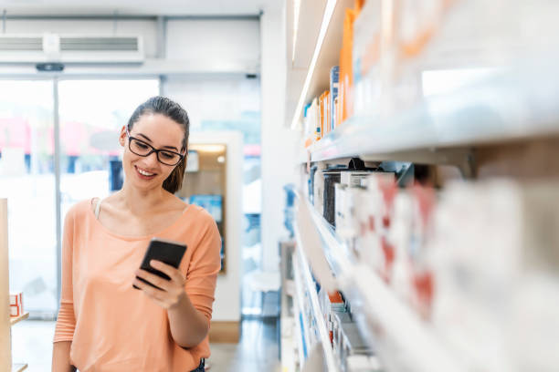 istock Cheerful female pharmacy customer uses phone in pharmacy 983596296