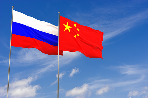 Russia and China flags over blue sky background. 3D illustration