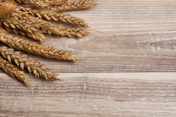 istock Sheaf of wheat ears on wooden table 983652762