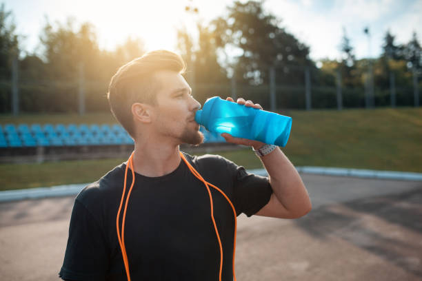 istock sportsman drinking water after training; 983658726