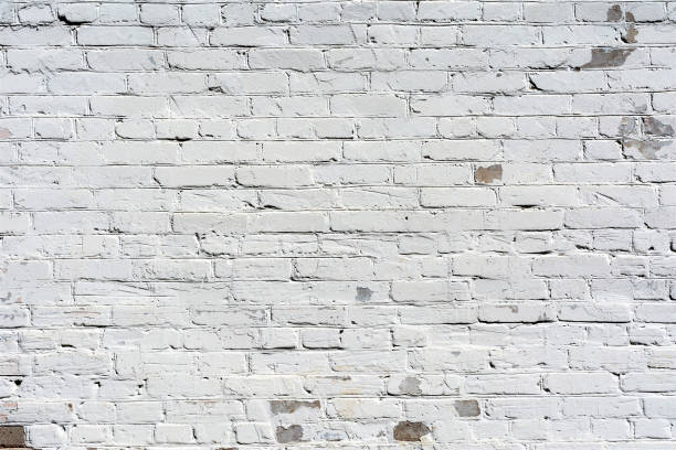 istock relief texture old brick wall painted with white paint, damages on the wall from the flow of water, abstract background 983669334