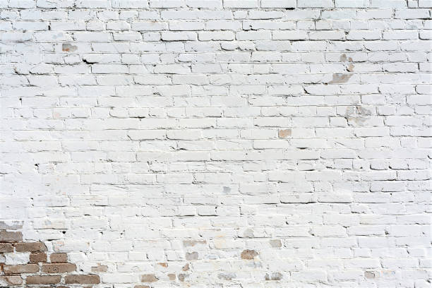istock relief texture old brick wall painted with white paint, damages on the wall from the flow of water, abstract background 983669344