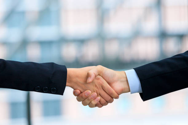 istock Shaking hands of businessmen and building background 983692996