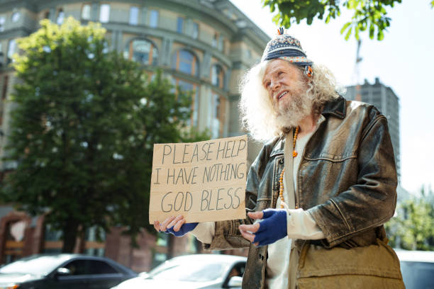 istock Long-haired homeless man standing near traffic asking for help 983699304