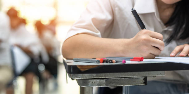 istock School exam student's taking educational test, admission test, thinking hard, writing answer in university classroom, education and world literacy day concept 983707636