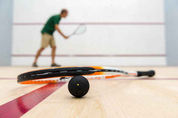 squash racket and ball on a court floor - racket ball indoors competition imagens e fotografias de stock
