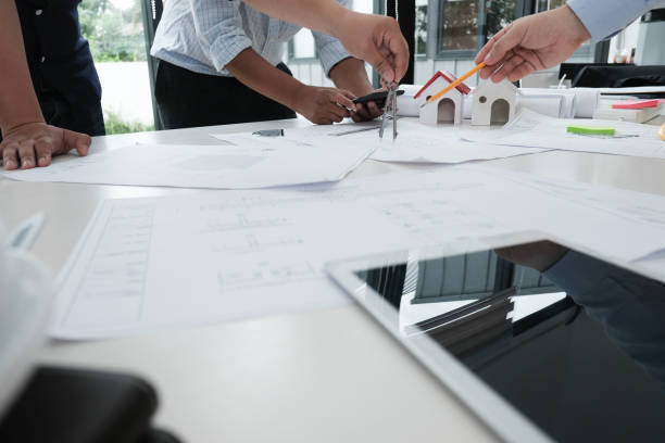 istock architect working on real estate project with partner at workplace. engineer discussing on living house blueprint at office. construction & building concept 983710388