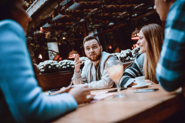 istock Group of Smiling Friends Having Conversation in a Coffee Restaurant 983752624