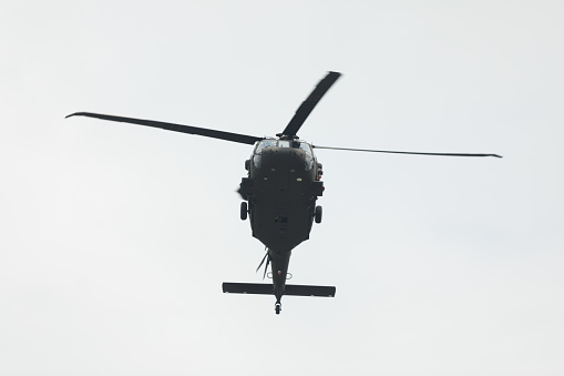 Indianapolis, Indiana, USA - May 26, 2018, A Sikorsky UH-60 Black Hawk does a fly by while a crew member takes photos with his phone out of the door at the Indy 500 Parade
