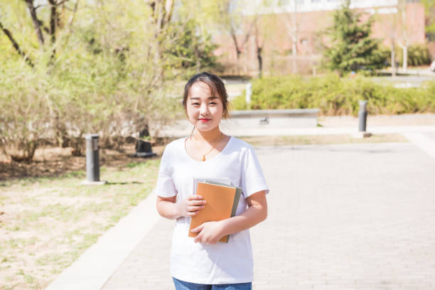 istock Female university college student holding books with campus background 983756482