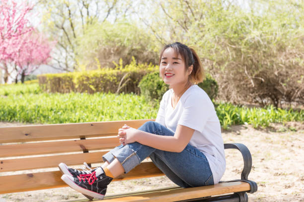 istock Young Asian girl on a bench in springtime 983756806