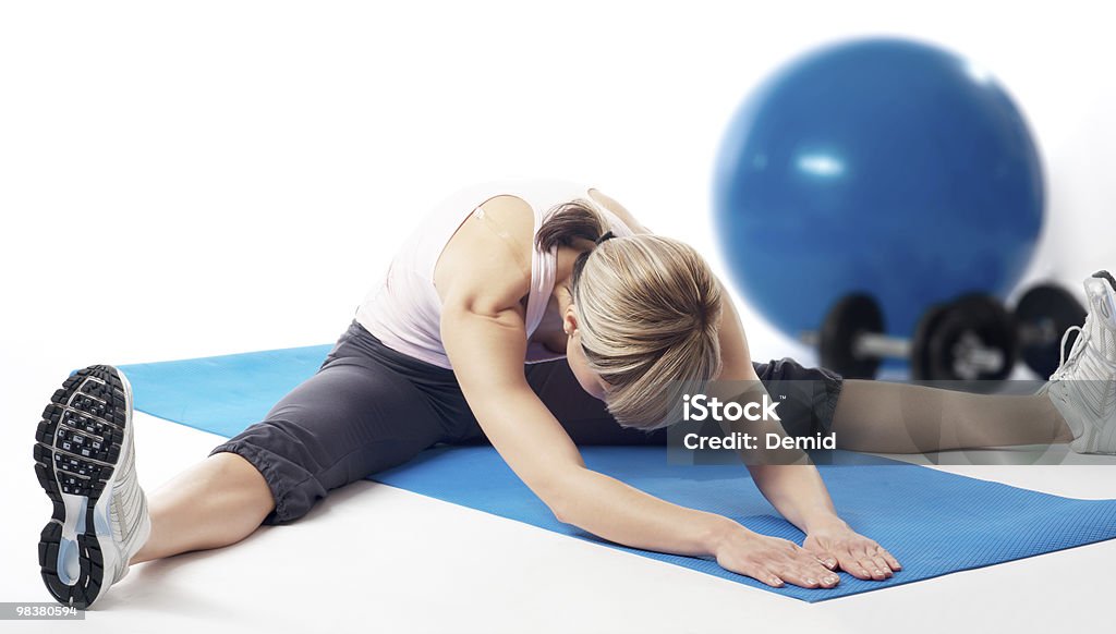 Sportswoman stretching Young beautiful sportswoman stretching on a mat. Adult Stock Photo