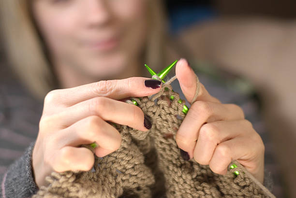 istock Young woman knitting a brown scarf with green needles 98380707