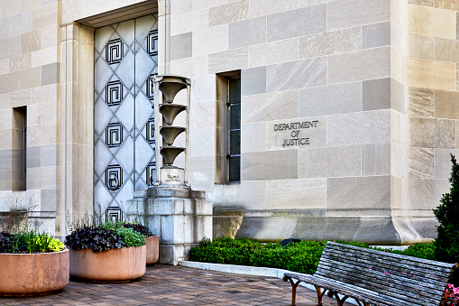 Washington DC, USA-June 5, 2018: Department of Justice building with the sign on the wall and a bench and large door