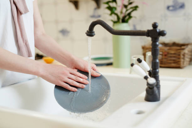 Washing plate Female hands holding grey porcelain plate while washing it under water over sink in the kitchen wash dishes stock pictures, royalty-free photos & images