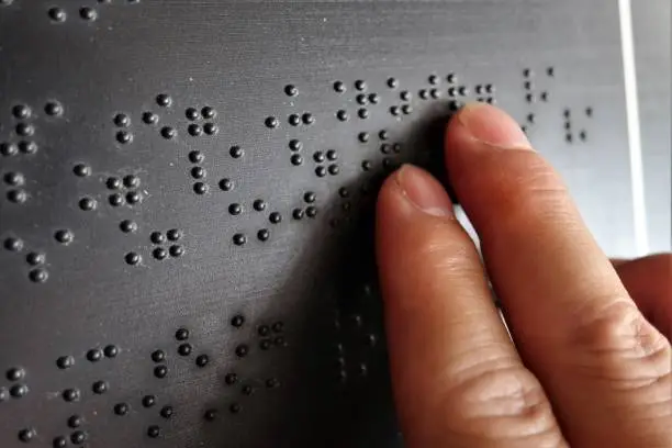 Close up of male hand reading braille text