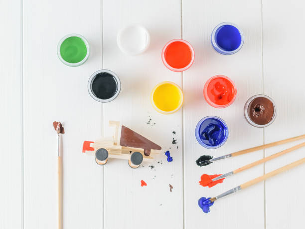 istock The process of coloring the machine with colorful gouache on a table. 983886316