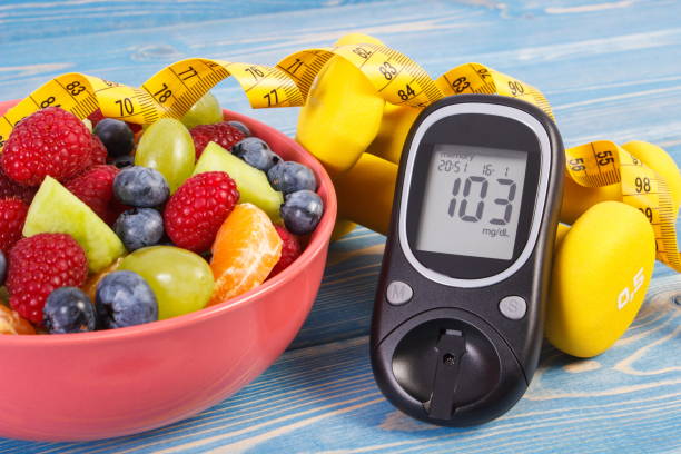 Fruit salad, glucose meter, centimeter and dumbbells, diabetes, healthy lifestyle and nutrition concept stock photo