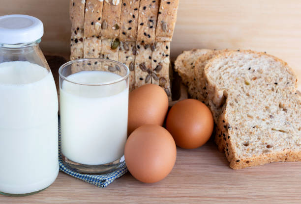 istock Bottle of milk, eggs, and bread on the wooden table. with copy space for text. 983900984