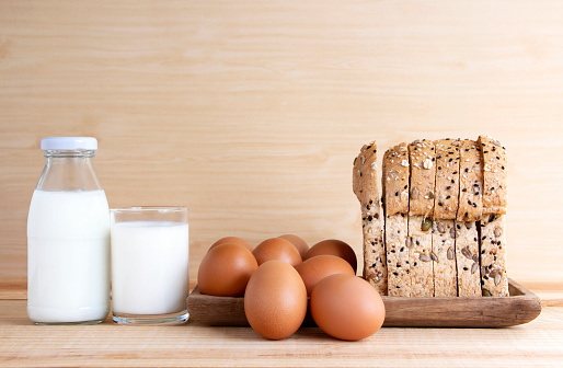 Milk, eggs, and bread on the wooden table. with copy space for text.