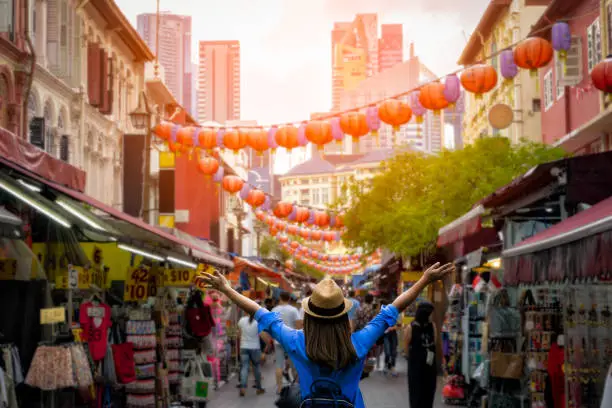 Photo of Young woman traveler with backpack and hat traveling into Chinatown at singapore city downtown. Travelling in Singapore concept