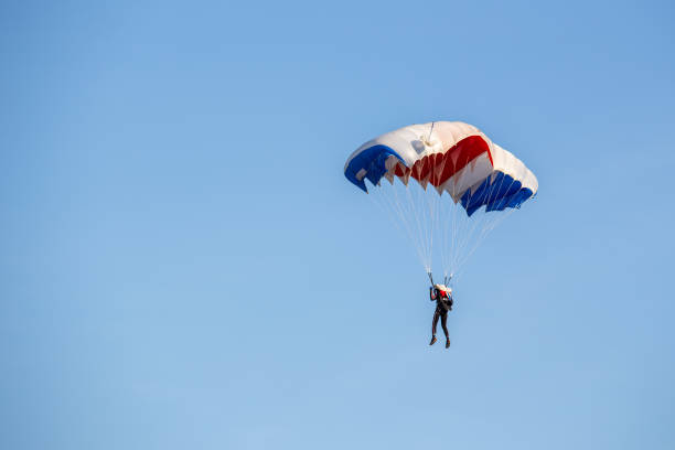 istock isolated skydiver  control colorful parachute gliding after free fall jump with blue sky background 983926282