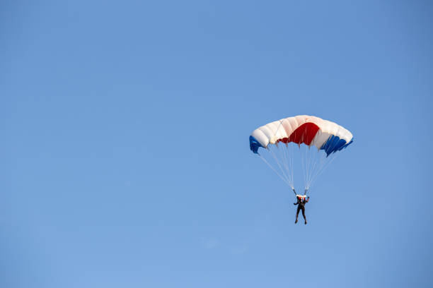 istock isolated skydiver  control colorful parachute gliding after free fall jump with blue sky background 983926312