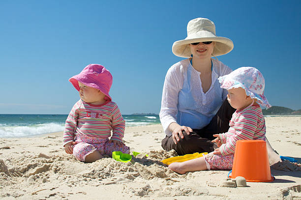 madre e due bambini in spiaggia - sun protection foto e immagini stock