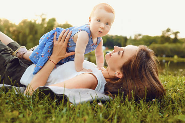 istock Mother and baby playing on grass in park 983958022
