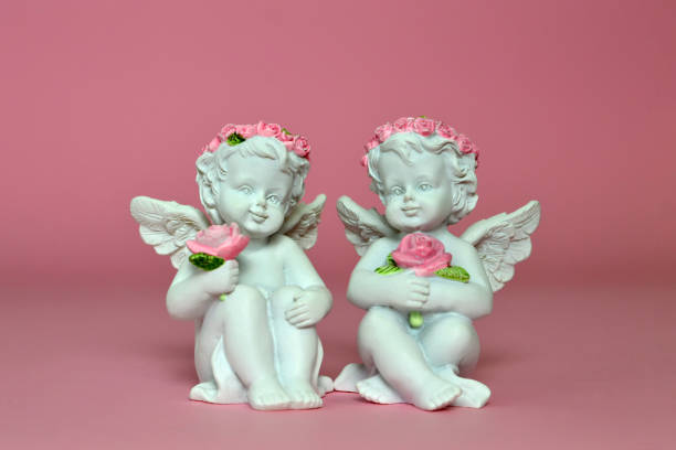 istock Two little angels holding roses on pink background 983958318