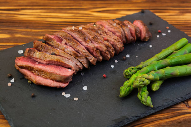 istock Grilled beef steak and asparagus on wooden background 983970872