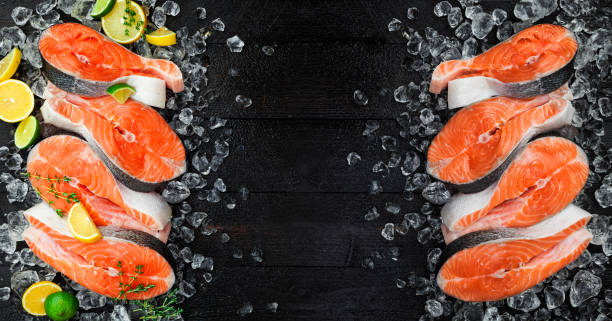 istock Fresh salmon steaks on ice, on black background. Top view. Copy space 983970910