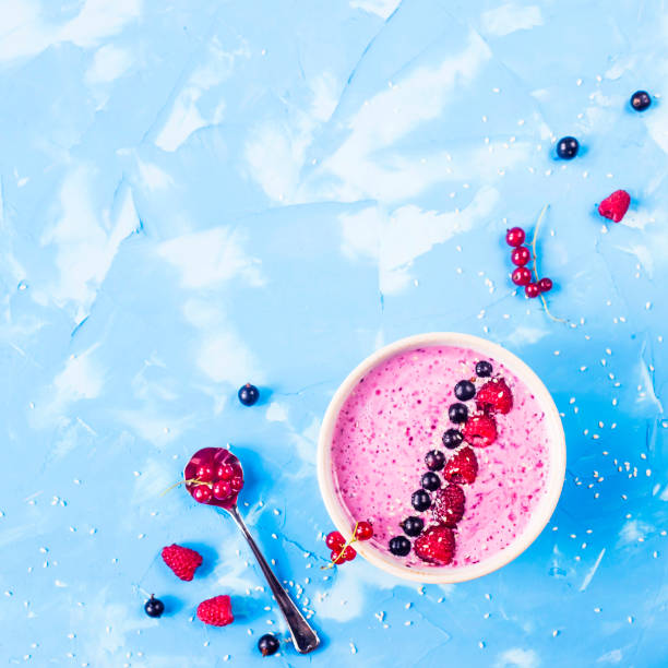 Berry smoothies with currants and raspberries on a bright blue background. Summer healthy snack. Copy space. Top view