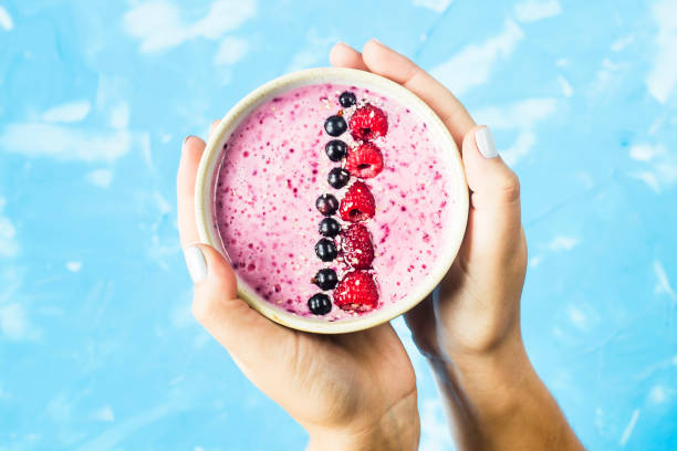 istock Berry smoothies with currants and raspberries in fwmalw hands on a bright blue background. Summer healthy snack. Top view 983991984