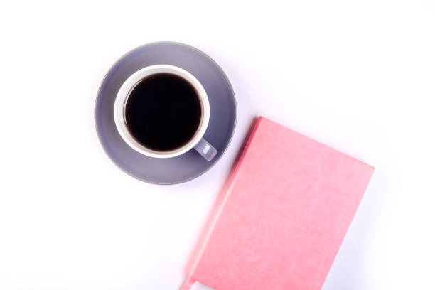 istock Workplace mockup with pink leather notebook and cup of coffee on white background top view. Flat lay with copy space. Feminine working style concept. 983995986