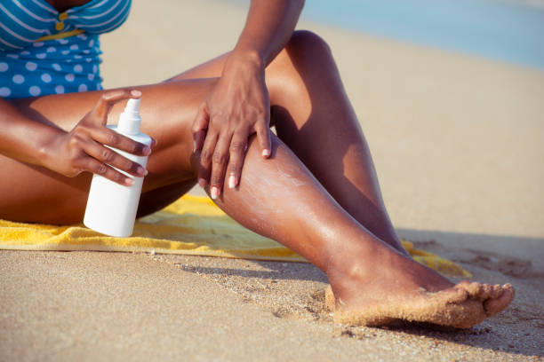 Sun protection spray to keep your skin healthy. Close up unrecognized woman applying, spraying sun protection cream on her legs. uv protection photos stock pictures, royalty-free photos & images
