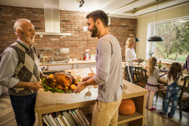 istock Happy men talking while carrying roasted turkey for Thanksgiving dinner with their family. 984004646